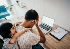 man at computer working stressed with his daughter on his back screaming