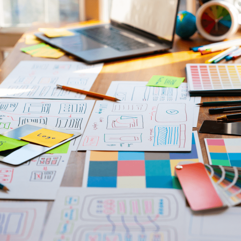 desk filled with documents, swatches and a laptop needed for planning website design