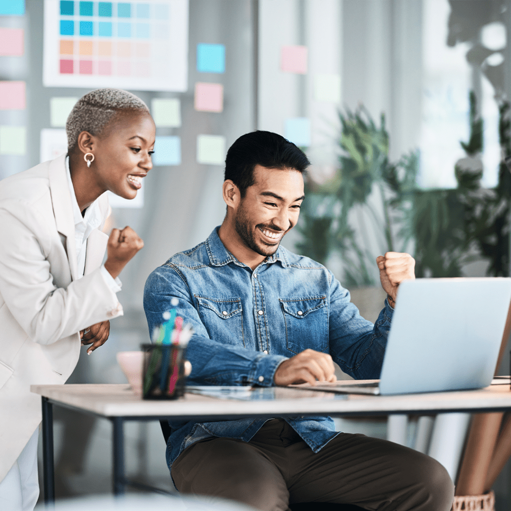 man sitting and woman standing at desk with fist up in victory, excited about new website design launch